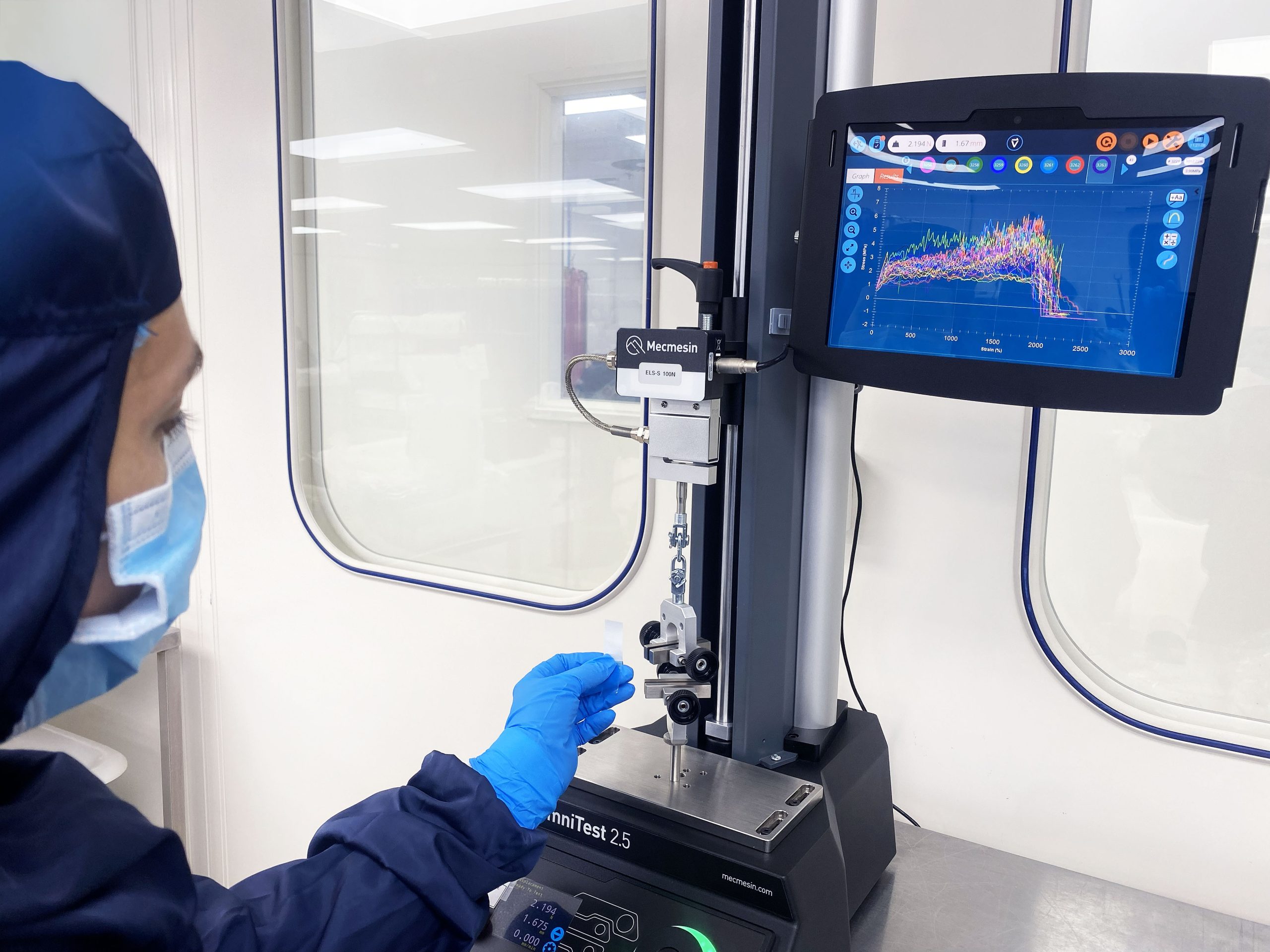 Side view of a Lab technician in PPE performing tests on a piece of machinery