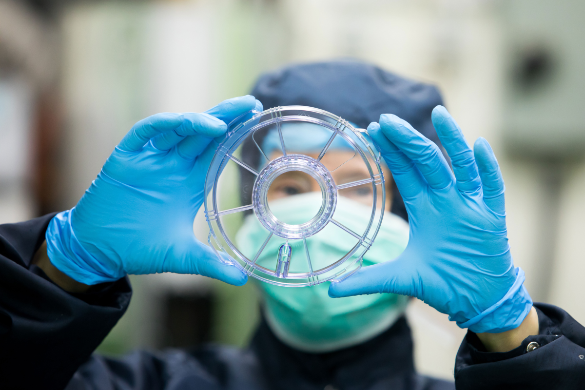 Cleanroom technician inspecting a transparent orthopaedic device, part of Meridian Medical’s ISO 13485-certified orthopaedic device manufacturing process.