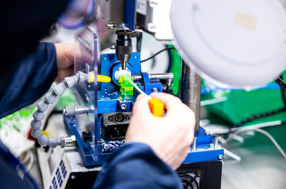 Cleanroom technician operating semi automated programable drill for hole punching urology devices such as catheterisation systems at Meridian Medical.