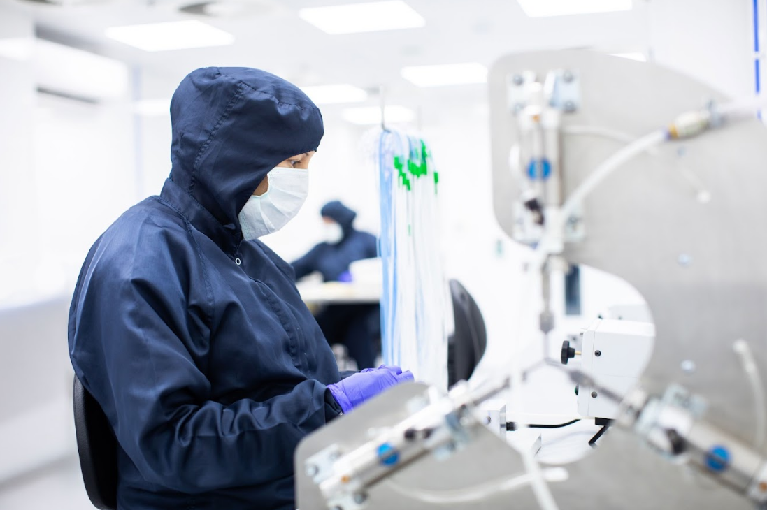 Cleanroom technician using a 3 way tube stretching machine to assemble medical tubing for single-use urology devices at Meridian Medical.